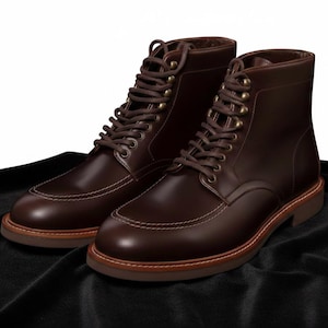 Könnte beinhalten: Ein Paar braune Lederstiefel mit klassischem Design. Die Stiefel haben einen Schnürverschluss, eine runde Spitze und weiße Kontrastnähte. Die Sohlen sind hellbraun.