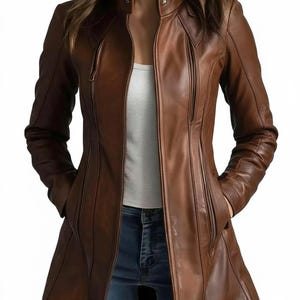 May include: A brown leather jacket with a tailored fit. The jacket features a stand-up collar, multiple zippered pockets, and a long, flowing design. The jacket is a rich, warm brown color and appears to be made of high-quality leather.