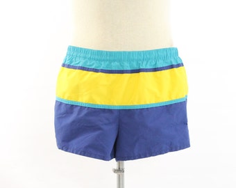 May include: Blue, yellow, and turquoise striped swim trunks. The trunks have an elastic waistband and a drawstring.