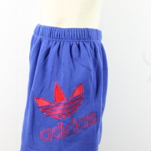 May include: Blue athletic shorts with a red and pink Adidas logo.