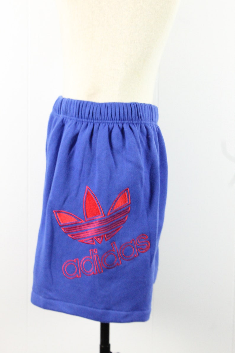 May include: Blue athletic shorts with a red and pink Adidas logo.