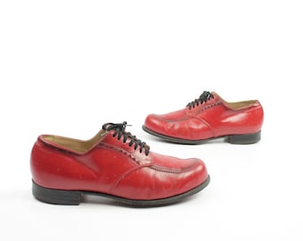 Pode incluir: Um par de sapatos de couro vermelho com cadarços pretos. Os sapatos têm um design clássico e estão em bom estado.