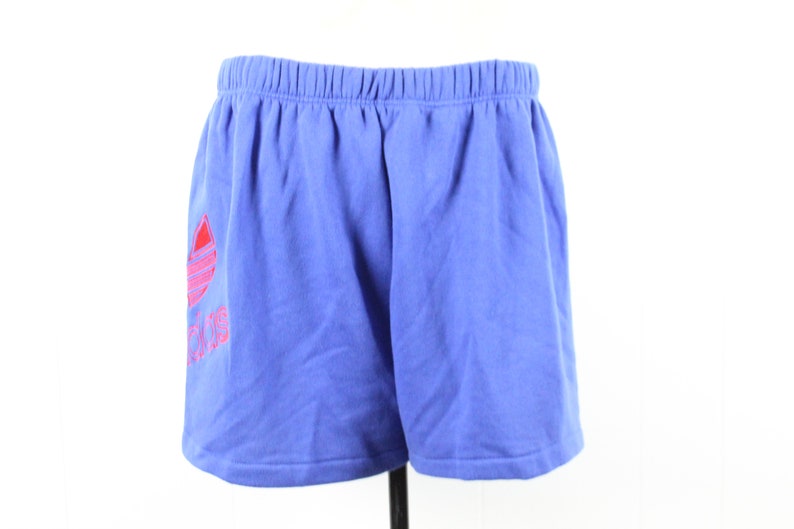 May include: Blue athletic shorts with a pink and red Adidas logo.