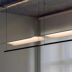 Puede incluir: Una lámpara colgante lineal que presenta dos paneles rectangulares alargados e iluminados, suspendidos por cables negros delgados. Debajo de los paneles de luz, una varilla negra horizontal y delgada corre paralela a la fuente de luz, creando un diseño geométrico en capas.