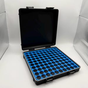 May include: Open black case with a blue foam insert featuring numerous circular cutouts. The case has a silver trim and a black handle. The case is open, revealing the interior, and is set against a white background.