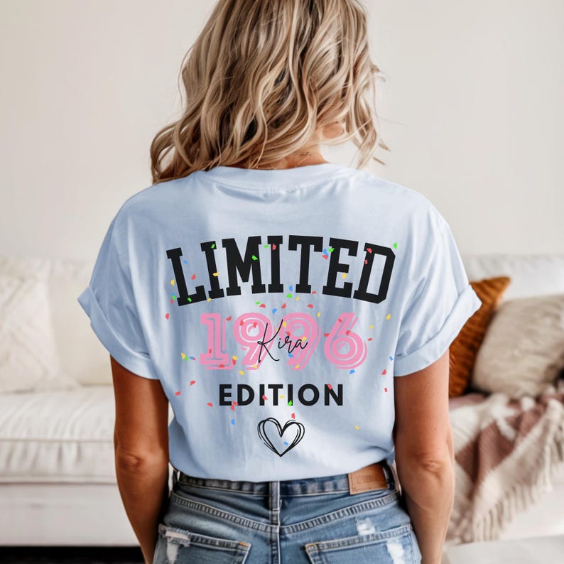 May include: Light blue t-shirt with the text "LIMITED 1986 Kira EDITION" in black and pink, with confetti and a heart graphic. The shirt is worn by a person with blonde hair.