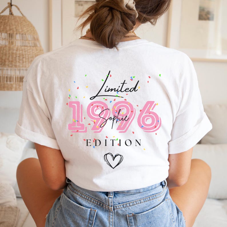 May include: White t-shirt with the text "Limited 1996 Sophie Edition" in black and pink. The design includes a heart and confetti. The shirt is a casual style.