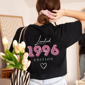 May include: Black t-shirt featuring the text "Limited 1996 Edition" in white and pink, with a white heart. The shirt is a casual style.
