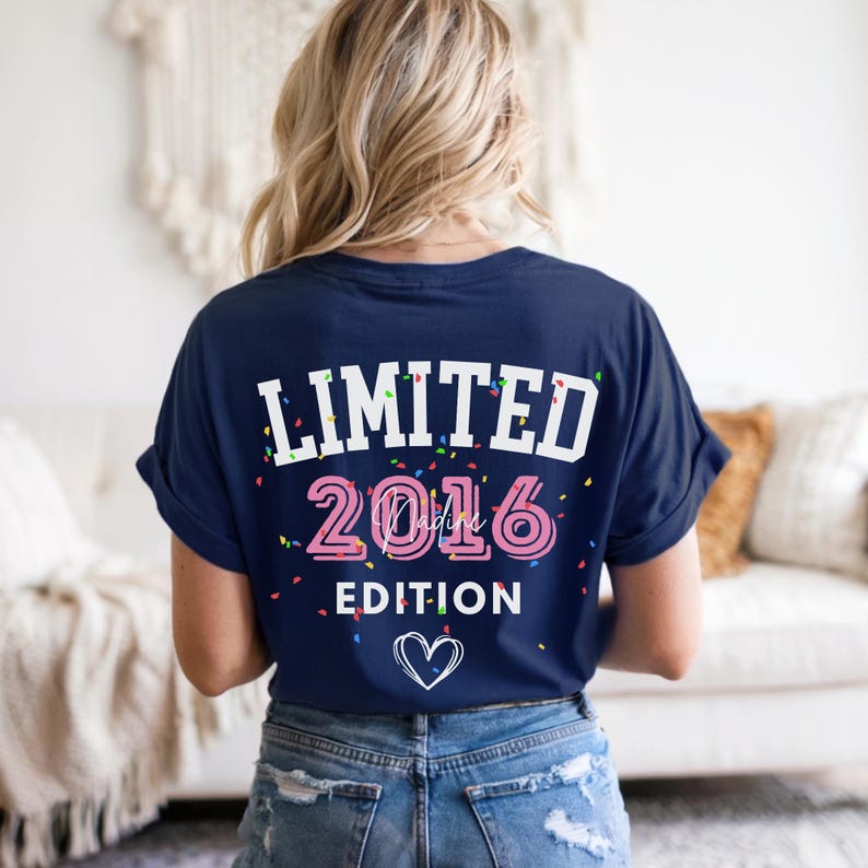 May include: Navy blue t-shirt with the text "LIMITED 2016 EDITION" in white and pink, with confetti accents and a heart graphic. The shirt is worn by a person with blonde hair and blue jeans.