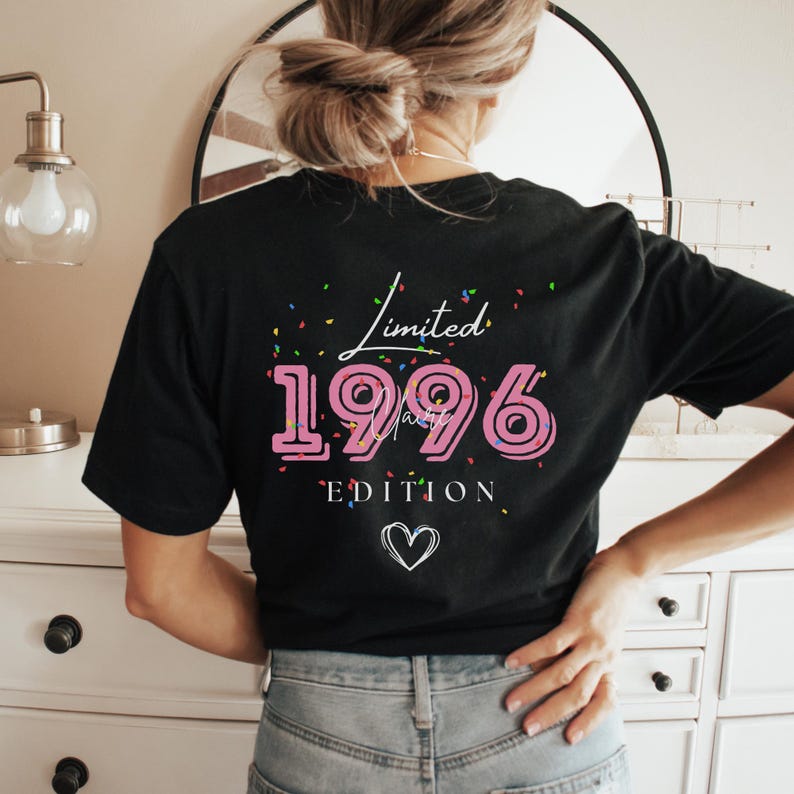 May include: Black t-shirt with the text "Limited 1996 Edition" in pink and white. The design includes confetti and a heart symbol. The shirt is a casual wear item.