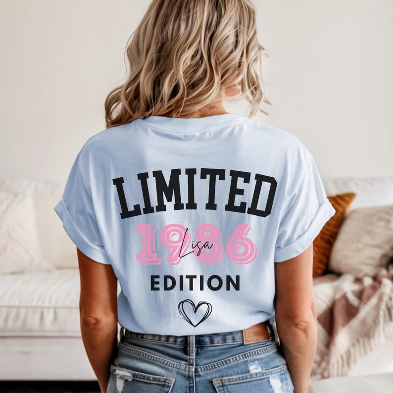 May include: Light blue t-shirt with the text "LIMITED 1986 Lisa EDITION" in black and pink. A heart outline is below the text. The shirt is worn by a person with blonde hair.