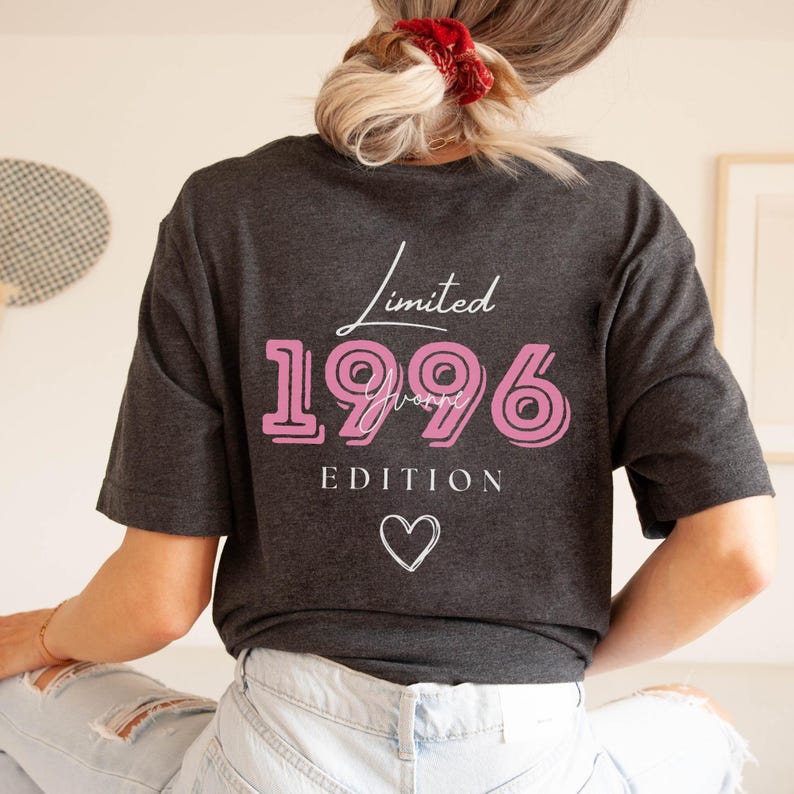 May include: Dark grey t-shirt featuring the text "Limited 1996 Yvonne Edition" in pink and white, with a white heart. The shirt has a relaxed fit.