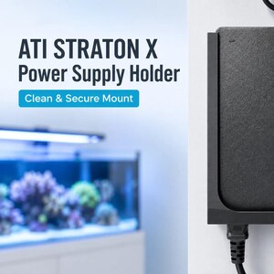 以下が含まれることがあります： ATI STRATON X用に設計された、壁掛け式の黒い電源ホルダー。ホルダーは長方形の黒い電源ユニットを固定しており、上下から電源コードが伸びています。左側のテキストには「ATI STRATON X Power Supply Holder」と記載されています。