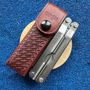 以下が含まれることがあります： 白のセラミックマグカップ、黒いハンドル、手書き風の「But First, Coffee」の文字。 マグカップは白い表面に置かれています。 温かい飲み物用です。