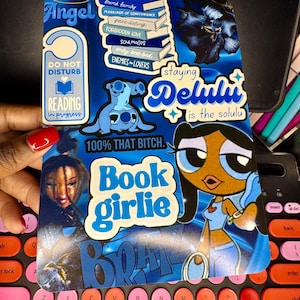 May include: A blue sticker with various graphics and text, including "Angel," "Do Not Disturb," and "Book Girlie." The sticker features cartoon characters, stacks of books, and the phrase "100% That Bitch."