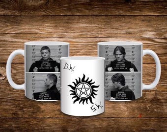 Puede incluir: Una taza de cerámica blanca con una fotografía policial en blanco y negro de un hombre sosteniendo un cartel que dice Little Rock Police, Little Rock AR, y un gráfico negro de un pentagrama dentro de un sol con las letras D.W. y S.W.