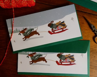 Lot de 2 cartes postales de Noël "Teckel tirant la luge des lapins".