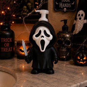 Peut inclure: Un distributeur de savon en forme de personnage v&ecirc;tu d'une robe noire &agrave; capuche et d'un masque blanc avec une bouche et des yeux allong&eacute;s. La figurine tient un couteau argent&eacute; dans sa main droite et poss&egrave;de une pompe en plastique transparent.