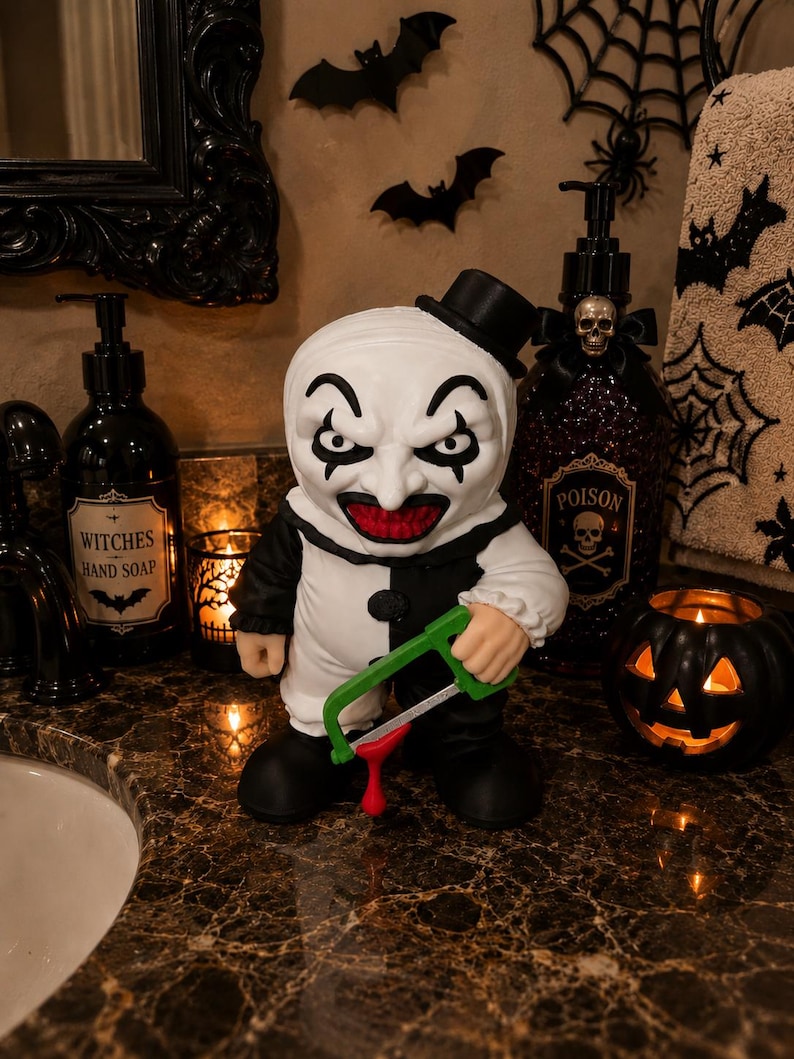 Peut inclure: Une figurine de clown au visage blanc, aux yeux maquill&eacute;s de noir et &agrave; la bouche rouge, portant une tenue noire et blanche et un petit haut-de-forme. La figurine tient une scie &agrave; m&eacute;taux verte avec une goutte rouge suspendue &agrave; la lame.