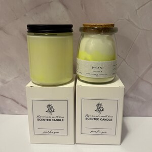 K&ouml;nnte beinhalten: Zwei Duftkerzen in Gl&auml;sern mit schwarzen Deckeln und Korken, auf wei&szlig;en Schachteln. Auf den Schachteln steht "Handmade with love SCENTED CANDLE" und "just for you". Die Kerzen sind gelb.