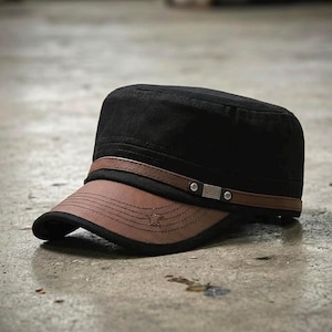 Puede incluir: Una gorra de estilo militar negra con visera de piel sintética marrón y una banda a juego en la parte delantera. La banda está decorada con dos tachuelas metálicas plateadas y una pequeña placa rectangular con el texto XS Fashion.