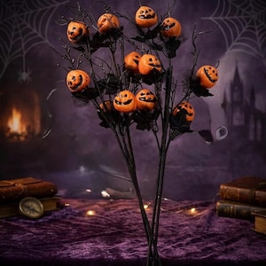 May include: A decorative Halloween tree featuring black branches adorned with multiple small orange jack-o'-lanterns. Each pumpkin has a carved face with black eyes and a mouth. The branches are accented with black mesh fabric, creating a dark, festive display.