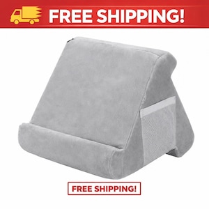 May include: A gray, plush reading pillow with a built-in pocket and a curved base. The pillow is designed to prop up books or tablets. The image also contains the text "FREE SHIPPING!"