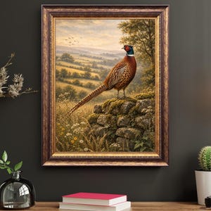 Peut inclure: Une peinture de paysage encadrée représentant un faisan à collier perché sur un muret de pierre moussue. L'oiseau possède un plumage brun, doré et bleu-vert irisé. L'arrière-plan montre une campagne vallonnée avec des arbres et un ciel doux.