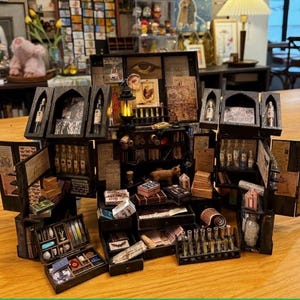 May include: A detailed miniature apothecary shop diorama. It features tiny bottles, books, drawers, and a cat figurine, all within a dark wooden structure. The scene has an antique and whimsical aesthetic, with a focus on intricate details.