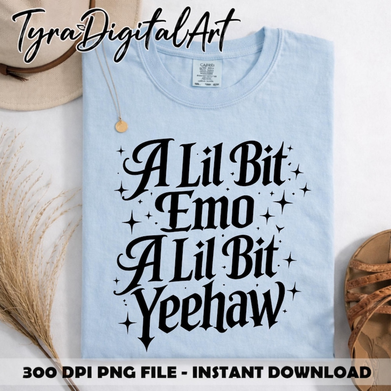 May include: Pale blue t-shirt featuring the phrase "A Lil Bit Emo A Lil Bit Yeehaw" in black lettering. The shirt has a round neck and is displayed with a hat and sandals.