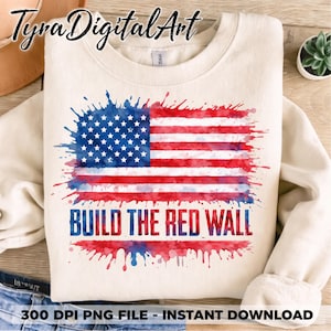 May include: Cream-colored sweatshirt featuring a watercolor American flag design in red, white, and blue. The text "BUILD THE RED WALL" is printed below the flag. The sweatshirt has a crew neck and long sleeves.