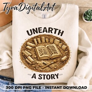 May include: Cream-colored sweatshirt with the words "UNEARTH A STORY" and a graphic of an open book, scrolls, and tools. The design is in shades of brown and tan, suggesting an archaeological or historical theme.