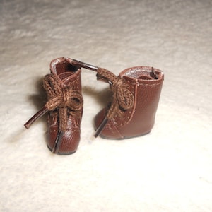 May include: A pair of brown leather boots with laces. The boots have a rounded toe and a low heel.