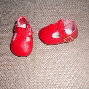 May include: A pair of red leather doll shoes with gold buckles.