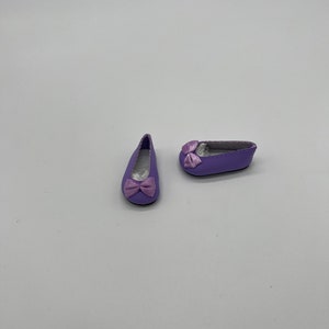 May include: A pair of purple ballet flats with a pink bow on each shoe.
