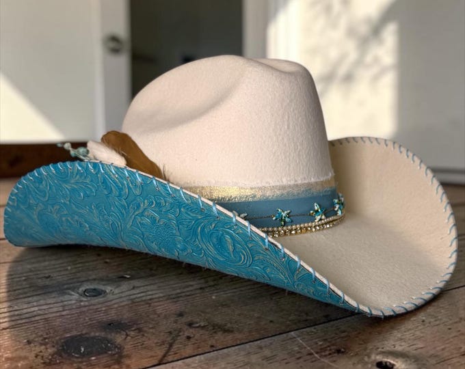 100% wool ivory cowboy hat with teal tooled leather handstitched to brim.