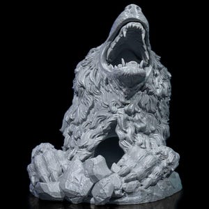 Könnte beinhalten: Graue Skulptur eines Bärenkopfes mit weit geöffnetem Maul, das scharfe Zähne zeigt. Das Fell des Bären ist detailliert, und die Skulptur steht auf einem Felsensockel. Der Hintergrund ist schwarz.