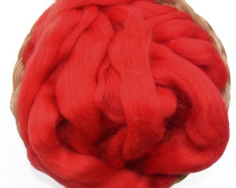 Puede incluir: Una cesta llena de vellón de lana rojo brillante. La lana es de un rojo intenso y rico y parece suave y esponjosa. La cesta es de material tejido natural, proporcionando un fondo contrastante. Ideal para artesanos textiles.