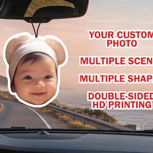 May include: A car air freshener featuring a baby's face wearing a white hat, hanging from a car's rearview mirror. The text on the right reads: "YOUR CUSTOM PHOTO, MULTIPLE SCENTS, MULTIPLE SHAPES, DOUBLE-SIDED HD PRINTING."