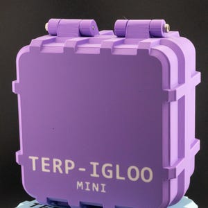 Puede incluir: Un contenedor TERP-IGLOO MINI púrpura con tapa con bisagras y base a juego. El contenedor tiene el texto "TERP-IGLOO MINI" en blanco. El contenedor está sobre una base azul claro con el mismo texto.