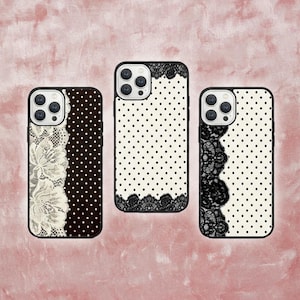 May include: Three phone cases with black frames. One case has a white lace design, another has black polka dots, and the third has black lace. All cases have a black frame and a camera cutout.