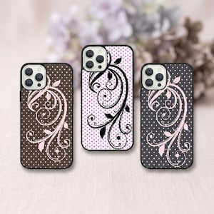 May include: Three phone cases with floral patterns. The cases have black borders and feature different colour schemes: brown with pink, light pink with black, and dark grey with pink. Each case has a polka dot pattern.