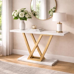 May include: A white marble-topped console table with gold-colored geometric legs. The table is decorated with a white vase of flowers, a lamp, and books. The table is 48 inches long.