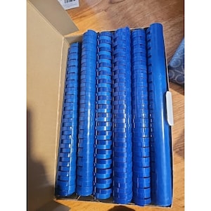 May include: A cardboard box containing multiple blue plastic binding spines. The spines, in various lengths, feature a slotted design for securing pages. They are a vibrant shade of blue, ideal for document binding.