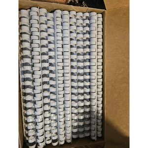 May include: A cardboard box containing a large quantity of white plastic binding spines. The spines are arranged in vertical rows. These spines are made of plastic and are designed for document binding, creating a neat, organised appearance.