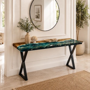 May include: A rectangular console table featuring a natural wood slab edge combined with a vibrant teal and blue resin river inlay. The table is supported by two black metal X-shaped legs and sits against a white wall beneath a round mirror.