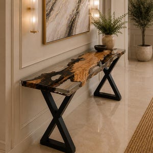 May include: A console table featuring a live edge wood slab with a glossy resin inlay, supported by two black metal X-shaped legs. The tabletop displays natural wood grain patterns in brown and tan tones contrasted by dark, translucent resin sections.