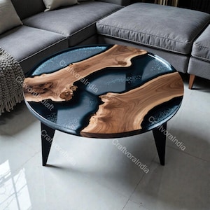 May include: An oval coffee table with a dark blue resin center and natural wood accents. The table has a black base with three angled legs. The wood grain is visible, and the resin has a glossy finish.