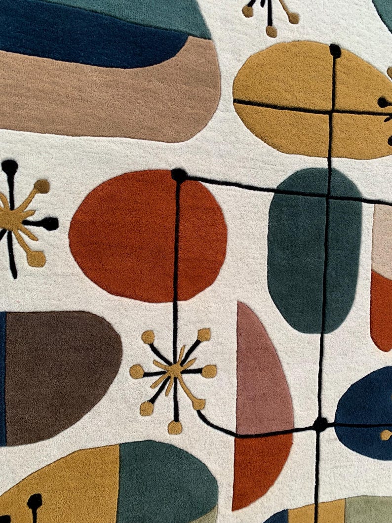Puede incluir: Primer plano de una colorida alfombra abstracta con un dise&ntilde;o moderno de mediados de siglo. La alfombra presenta varias formas en tonos de azul, marr&oacute;n, naranja, amarillo y rosa sobre un fondo blanco. L&iacute;neas negras conectan las formas, creando un patr&oacute;n &uacute;nico.