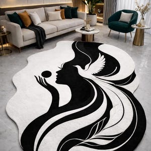 Op de afbeelding: Een groot, abstract vloerkleed met een zwart-wit ontwerp. Het vloerkleed toont een silhouet van een vrouw die een bol vasthoudt, met een duif en vloeiend haar. Het vloerkleed bevindt zich in een moderne woonkamer.